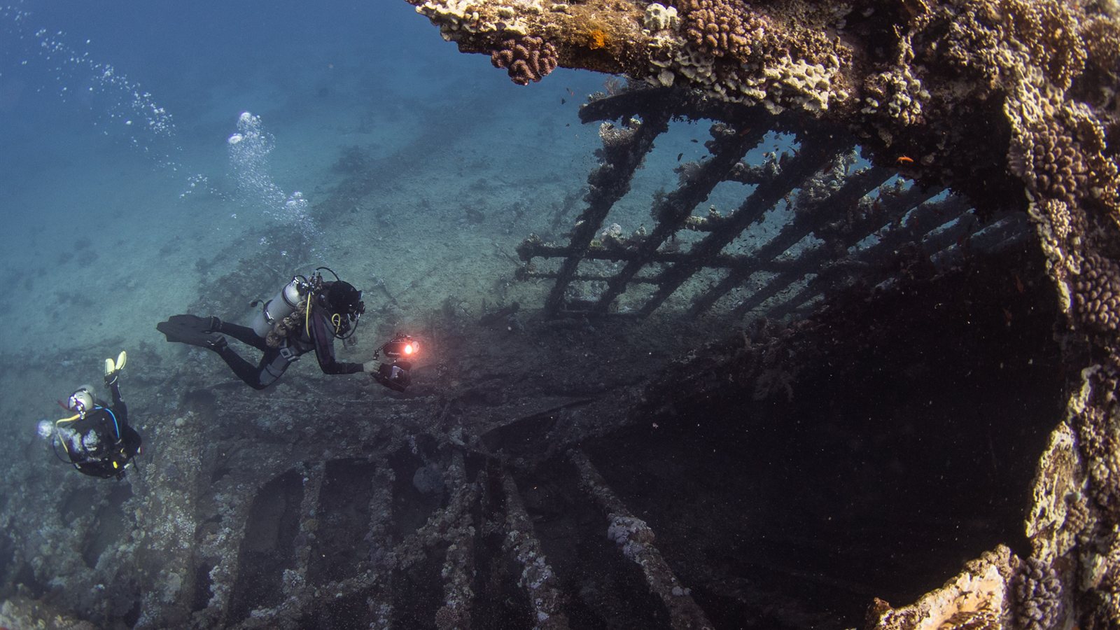 Divers exploring the hull of a sunken wreck