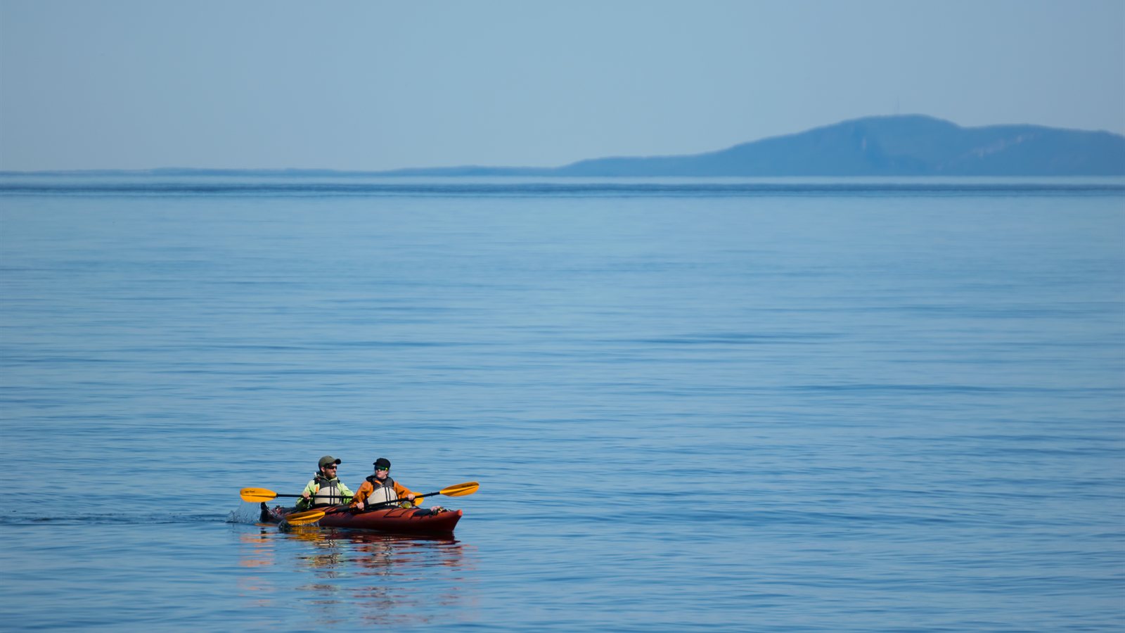 Two paddlers in a tandem kayak on flat open water